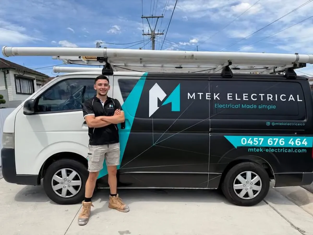 MTEK electrician standing beside the branded company van