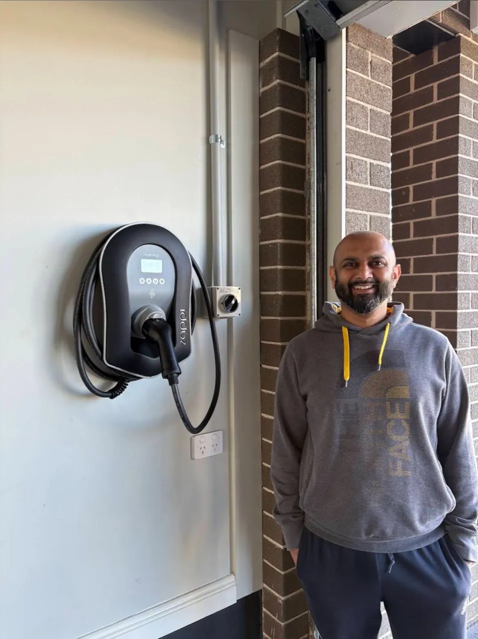 A customer beside a Zappi EV charger installed by MTEK